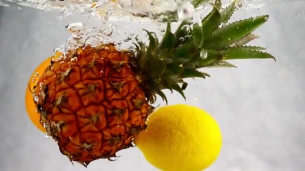 パイナップル レモン オレンジの落下への水しぶきとスローモーションで泡水 — ストック動画