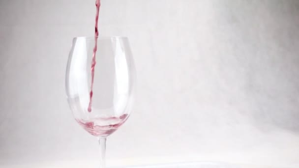 Red wine is pouring into glass on white background. Slow motion — 图库视频影像