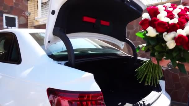 Homme met dans la voiture un grand bouquet de roses rouges — Video