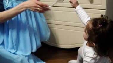 Genç bir anne bebek kızı mavi elbisesi ile gösterir.
