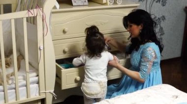 Genç anne küçük kız bebek şifonyeri kıyafetlerden çeker