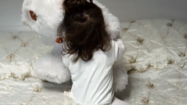 En liten flicka kramar sin favorit mjuk Björn leksak — Stockvideo