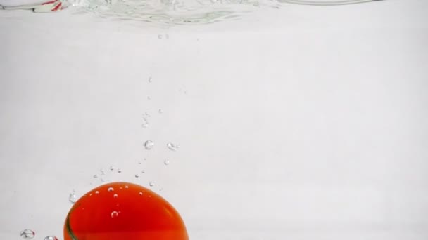 Eine reife rote Tomate rotierender Tauchgang unter Wasser links, Zeitlupe Nahaufnahme — Stockvideo