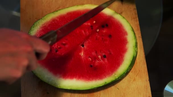 Skär skivor vattenmelon i hälften med en kniv — Stockvideo