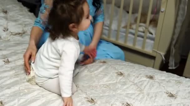 Malá holčička si hraje s balonem, který sedí na posteli — Stock video