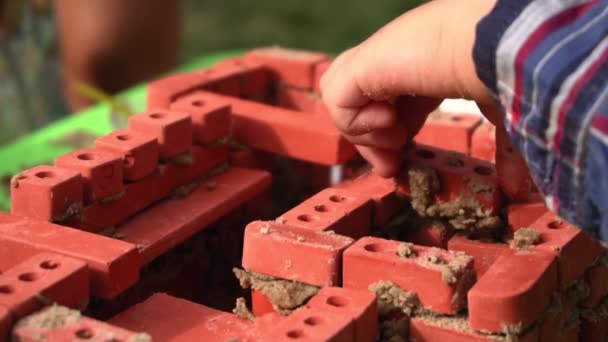 Dospělí pomáhají dítěti stavět z hraček s cihlovými kameny — Stock video
