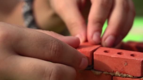 Barnet sätter försiktigt en liten leksak tegel — Stockvideo