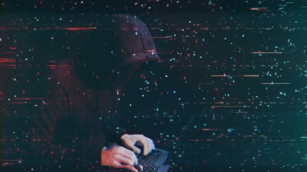 За компьютером работает хакер с черной маской на лице — стоковое видео