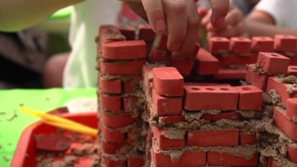 Niño desmonta juguete fortaleza de ladrillos pequeños — Vídeos de Stock