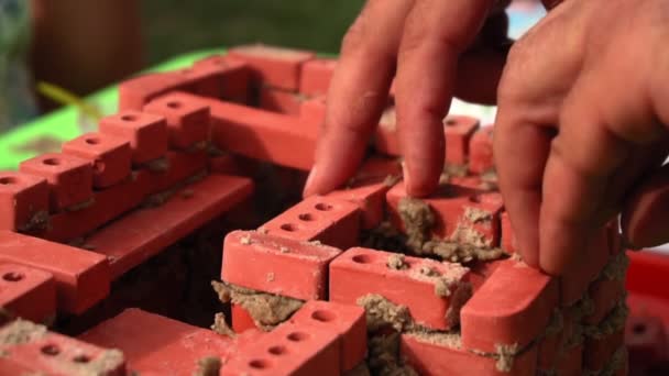 Мужчина строит игрушечное здание — стоковое видео