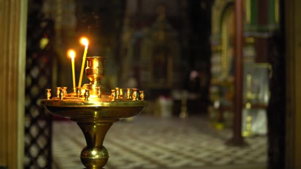 Deux bougies dans l'église sur un chandelier sur fond d'église flou à l'intérieur — Video