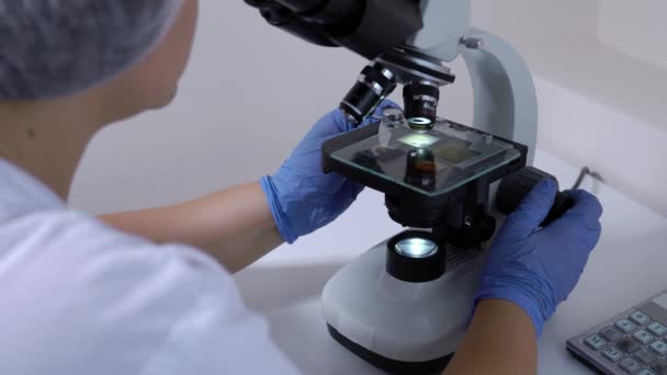 認識できない女性の実験室の技術者は、医療検査使用顕微鏡を行います. — ストック動画