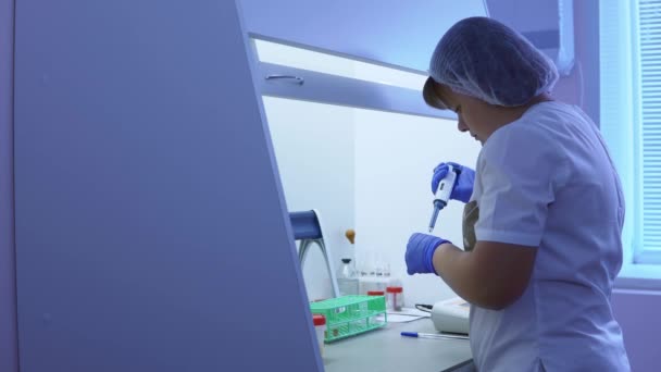 Femme technicienne de laboratoire fait un test médical avec des tubes et une pipette automatique . — Video