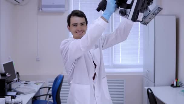 Young man laboratory technician is dancing in lab with microscopes in hands. — Stock Video