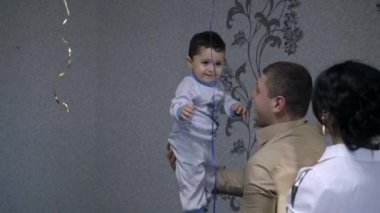 Erkek bebek babalar elinde duruyor denge hile yapmak tutar ve anne bakarak.