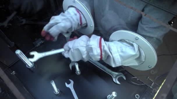 Man wearing gloves from the astronaut suit tries to pick up a wrench to unscrew the nut. Attraction in the space Museum. — Stock Video