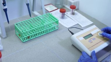 Laboratuar teknisyeni özel ekipmandaki test tüplerinden testleri kontrol eder