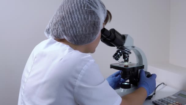 Vrouw chemicus in het laboratorium werkt met een Microscoop — Stockvideo