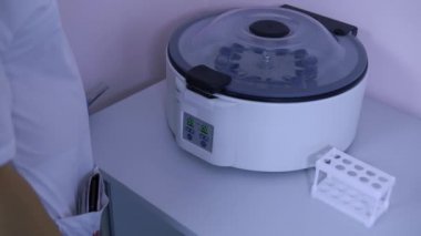 Laboratuvar teknisyeni bir santrifüj test tüpleri alır ve bir tripod üzerine koyar