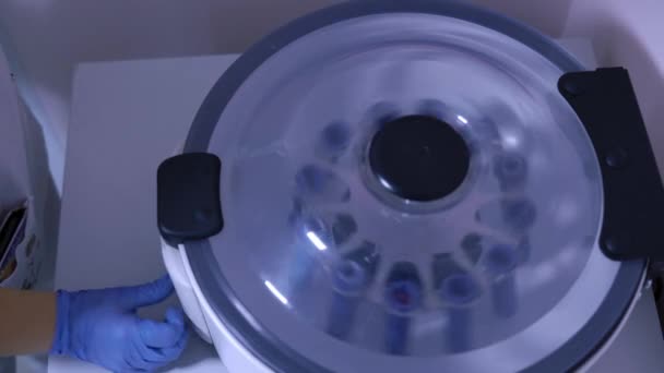 Лаборант в лаборатории нажимает кнопку старта на центрифуге — стоковое видео