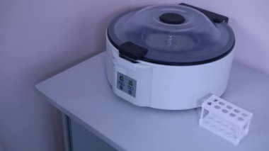 Laboratuvar teknisyeni bir laboratuvarda santrifüj üzerinde bir düğmeye basar