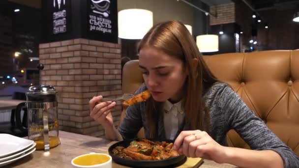 Portrait de jeune fille mange de savoureuses pommes de terre frites servies sur une poêle dans un café de la ville — Video