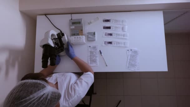 Woman laboratory technician comes to his workplace in lab and sit down — Stock Video