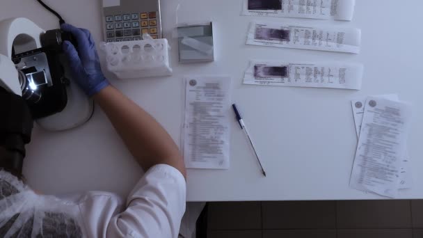 顕微鏡および文書が付いている実験室のテーブル労働者、上の眺め — ストック動画
