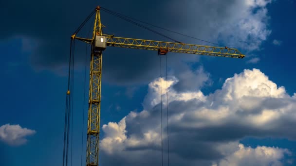 Gele constructie kraan werkt tegen blauwe hemel met wolken timelapse — Stockvideo