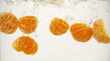 Mandarine dilimleri kabarcıklar ve sıçramaları, yavaş hareket yakın çekim ile suya batırılır