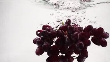 Yavaş çekimde kırmızı üzümler. Üzüm demet kabarcıkları ile suya batırılır.