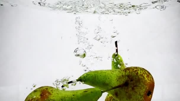 Зеленая груша погружается в воду с пузырьками на изолированном белом фоне. Видеозапись груш в замедленной съемке . — стоковое видео