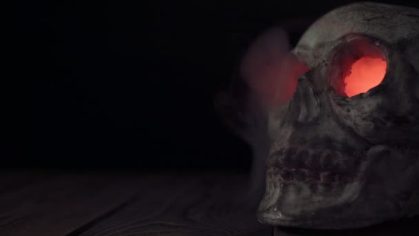 煙が出る燃える目を持つ古い人間の頭蓋骨クローズアップ — ストック動画