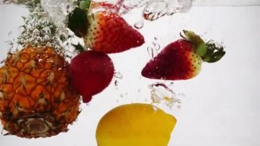 Ananas, limon ve çilek yavaş çekimde kabarcıklarla suda dönüyor..