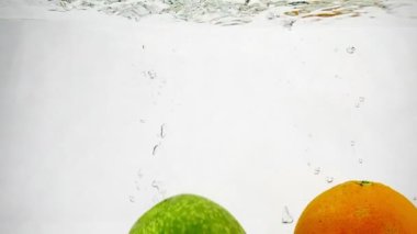 Ananas ve elma bir sürü kabarcıkla suya düşer. İzole edilmiş beyaz arkaplanda meyve videosu.