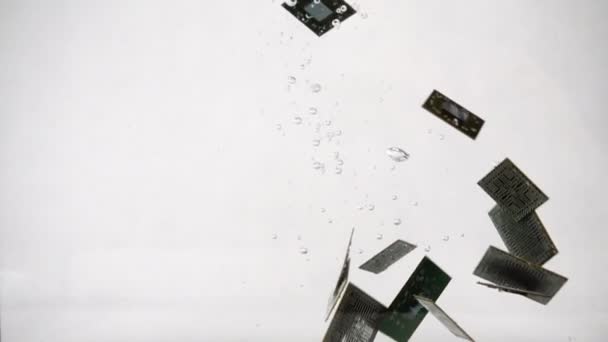Voděodolné počítačové mikročipy padající do vody, zpomalený pohyb na bílém pozadí — Stock video