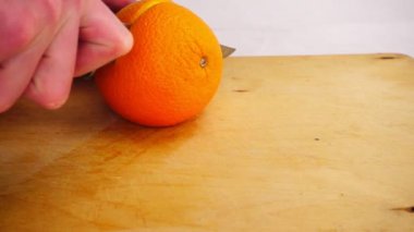 Tahta kesme tahtasındaki bıçakla taze portakalı dilimlemek, ağır çekim.