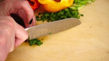 Tahta kesme tahtasındaki bıçakla yeşil soğan doğramak.