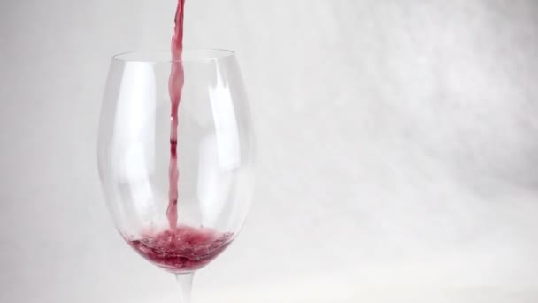 葡萄酒倒入一个白色背景的透明的大玻璃杯中 — 图库视频影像