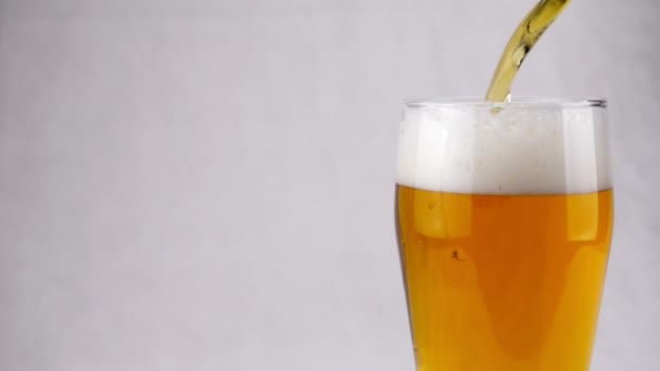 Bier is gieten in glas op witte achtergrond. Slow motion — Stockvideo