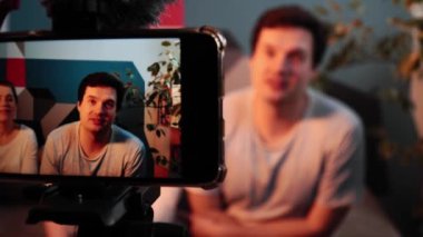 Hamile kadın ve kocası telefonda duygusal bir video çekiyorlar.