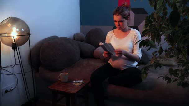 La mujer embarazada está desempaquetando la instrucción a las píldoras y toma la ampolla — Vídeos de Stock