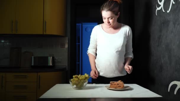 Mujer embarazada toma las uvas y luego toma el plato con pastel también — Vídeos de Stock