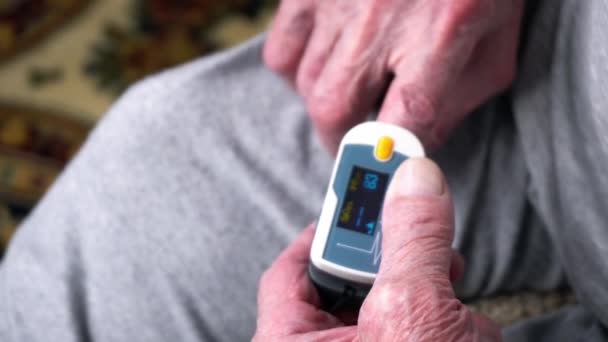 Old man is using pulse oximeter at his finger to measure his pulse — Stock Video