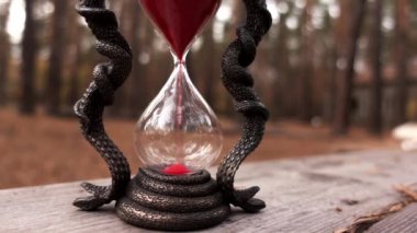 Kırmızı kumlu el yapımı kum saati ahşap masada duruyor.