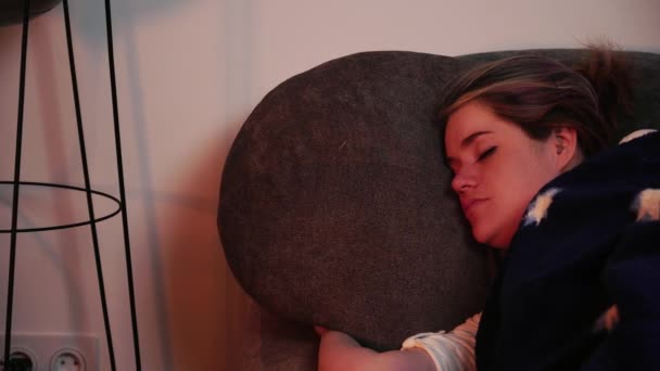 Женщина лежит на диване и спокойно спит под одеялом — стоковое видео