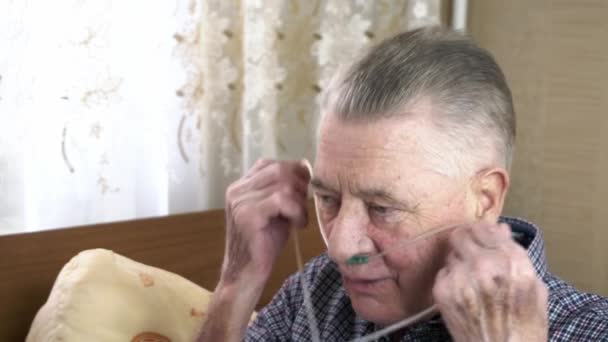 O persoană în vârstă pune un cateter nazal cu oxigen pe cap acasă — Videoclip de stoc