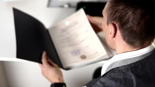 Мужчина открывает черную папку и смотрит на документы в ней . — стоковое видео