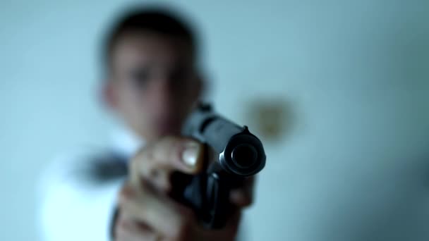 Преступник держит пистолет в правой руке стоя на белом фоне — стоковое видео