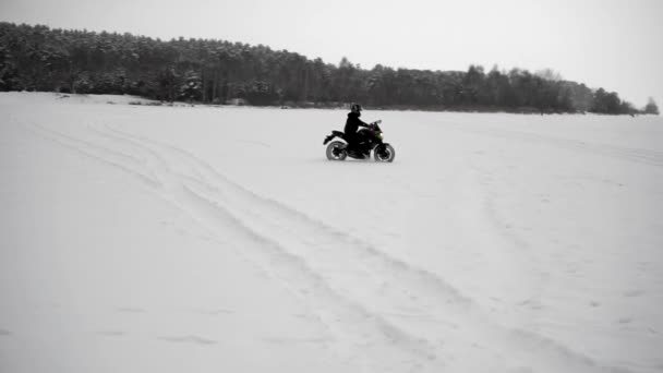Человек едет на мотоцикле зимой по полю в снегу — стоковое видео